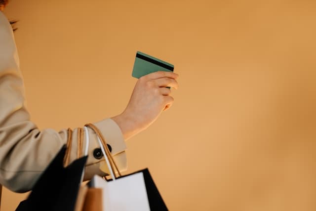 A person holding shopping bags and a credit card.